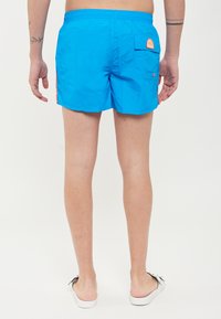 Shorts da nuoto blu realizzati in tessuto leggero, dotati di una vita elasticizzata, una tasca posteriore e dettagli arancioni a contrasto.