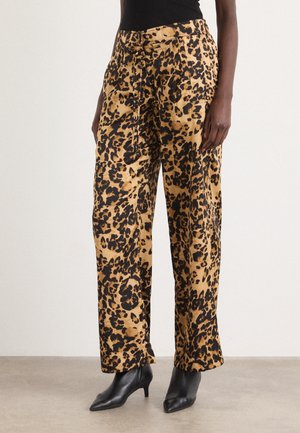 Woman wearing high-waisted wide-leg pants with a tan and black leopard print, paired with black pointed-toe heeled ankle boots.