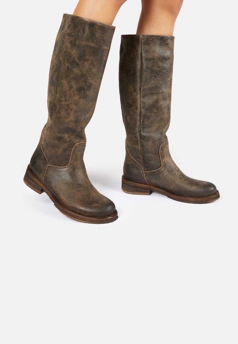 Bottes hautes jusqu'au genou en cuir marron vieilli, avec un bout arrondi, un talon empilé et des coutures visibles le long des coutures.