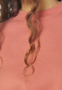 Top rosa a maniche corte in misto cotone con texture a coste e scollatura rotonda, caratterizzato da dettagli di cucitura sottili.