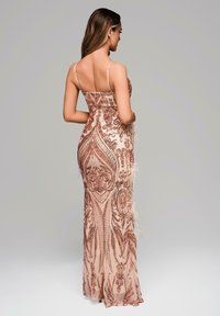 Roze-gouden avondjurk met ingewikkelde glazen patronen en veren accenten. Beschikt over dunne bandjes en een getailleerd silhouet.