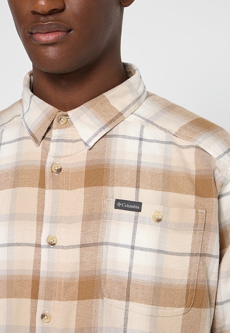 Camisa de cuadro en tonos marrón claro y crema con dos bolsillos en el pecho, cuello clásico y etiqueta de logo de Columbia en el bolsillo izquierdo.