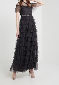 Vestido negro de tul con volantes y lunares, con un cuerpo ajustado y mangas cortas. Adornado con un cinturón floral.