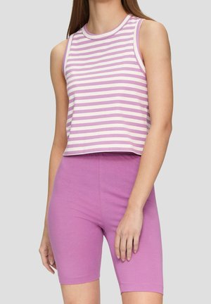 Kobieta ubrana w bezrękawnikowy, lawendowo-biały crop top w paski oraz jednokolorowe, dopasowane szorty w kolorze lawendy na jednolitym tle.