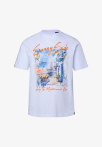 Camiseta blanca con un estampado colorido de una calle mediterránea junto al mar, que muestra una cesta de limones y el texto "Sunny Side" y "Living The Mediterranean Life".