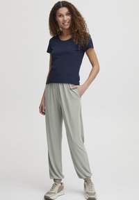 Marinblå kortärmad t-shirt i kombination med ljusgrå joggbyxor med elastiska muddar och sidofickor, bärs med grå sneakers.