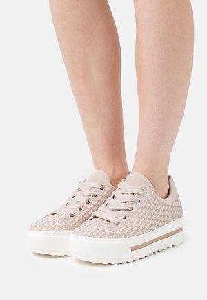 Beige vävda sneakers med en strukturerad yta, rund tå och platåsula. Har silverfärgade öljetter och matchande snören.