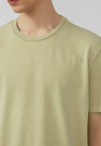 Helles grünes T-Shirt mit kurzen Ärmeln aus weicher Baumwolle. Hat einen runden Halsausschnitt und eine glatte Textur mit minimalen Nähten.