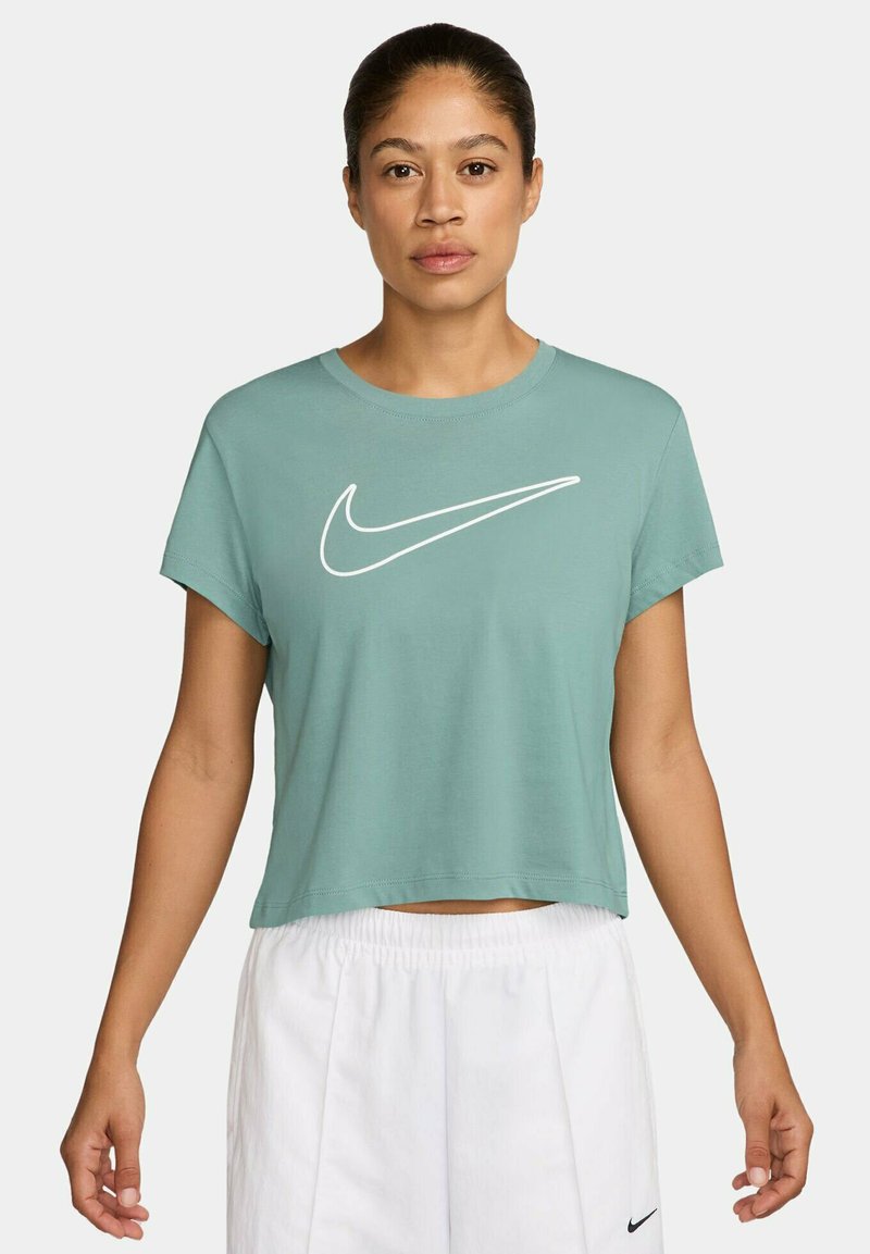 T-shirt verde cropped con collo rotondo e maniche corte; presenta un grande logo Nike bianco sul davanti. Materiale in cotone morbido.