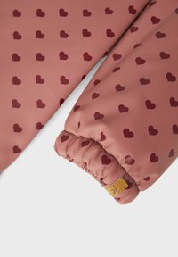 Rosa vattentålig jacka med ärmar som har elastiska muddar och ett vinrött hjärtmönster, med en liten brun etikett på ena mudden.