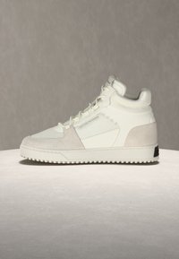 Λευκό αθλητικό παπούτσι με κορδόνια, σιλουέτες από σουέντ, επενδυμένο κολάρο και ραβδωτή σόλα σε ουδέτερο φόντο.