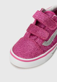 Baskets à paillettes rose avec des bandes Velcro, accent en argent, semelle blanche et texture lisse. La tige présente une finition brillante et scintillante.