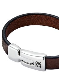 Pulsera de cuero marrón con borde negro, que cuenta con un cierre plateado de diseño elegante y marca grabada. Textura suave en toda la superficie.