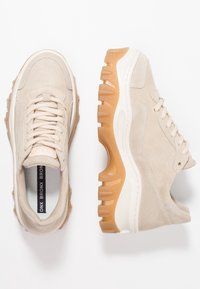 Beige Wildledersneaker mit strukturierter Oberfläche und dicker Gummisohle in Kaugummi-Optik. Verfügt über gepolsterten Schaft und Schnürsenkel aus Kordel. Minimalistisches Design.