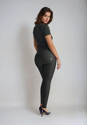 Mustat istuvat leggingsit, joissa on sileä pinta, kaksi takataskua ja pieni logoyksityiskohta. Yhdistetty tummaan istuvaan toppiin ja korkokenkiin.