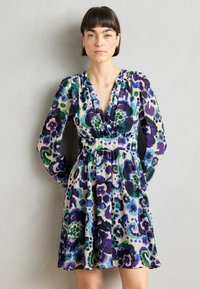 Robe à motifs floraux avec un décolleté en V profond, des manches longues et une taille ajustée, fabriquée en tissu léger dans des tons de violet, vert et bleu.