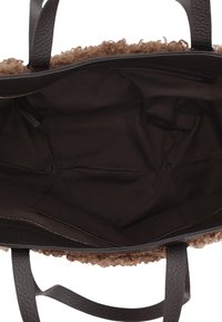 Brown tote bag with plush textured interior and smooth leather handles. Features a single compartment and a zippered pocket along the side.