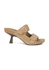 Mule in suede beige con punta aperta, dotata di due cinturini regolabili con fibbia e tacco affusolato di 7 cm. Superficie testurizzata, suola liscia, dettagli minimal.