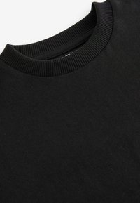 Felpa nera in cotone con colletto a girocollo a coste. Texture liscia e design informale, priva di grafiche o decorazioni visibili.