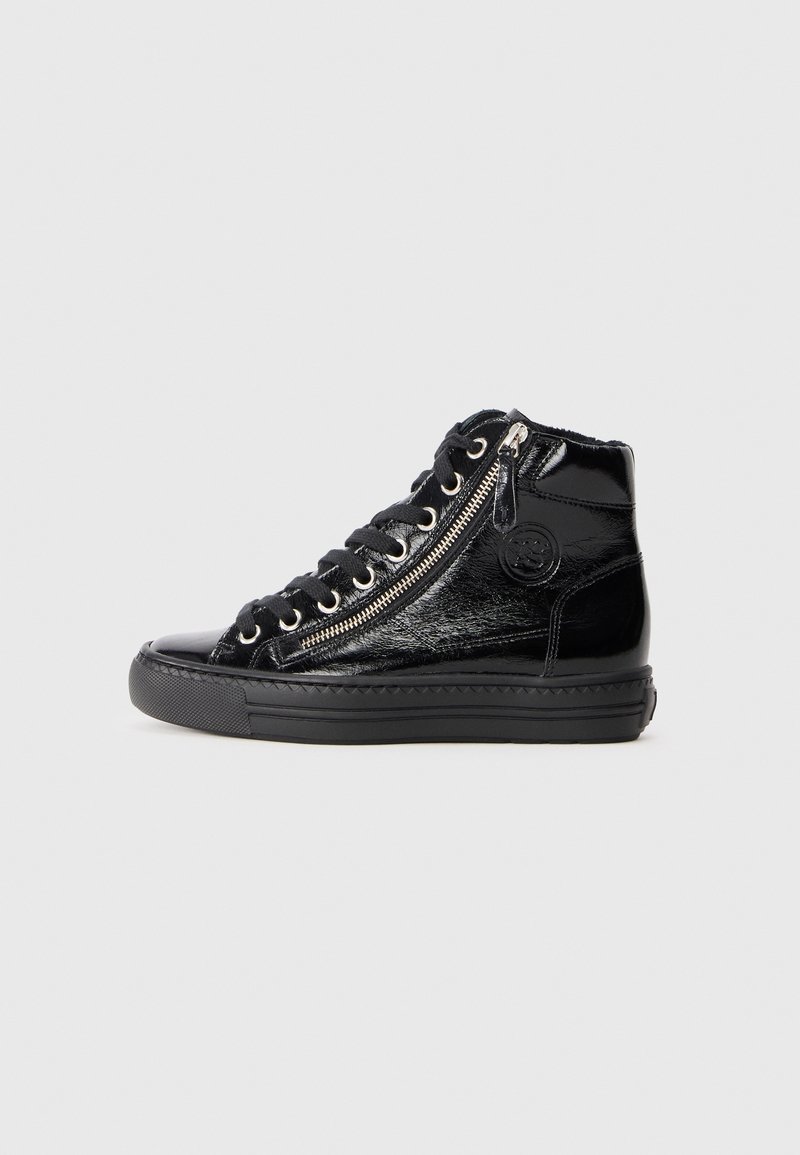 Basket montante en cuir verni noir avec semelle épaisse, fermeture éclair latérale et lacets noirs sur fond uni gris clair.