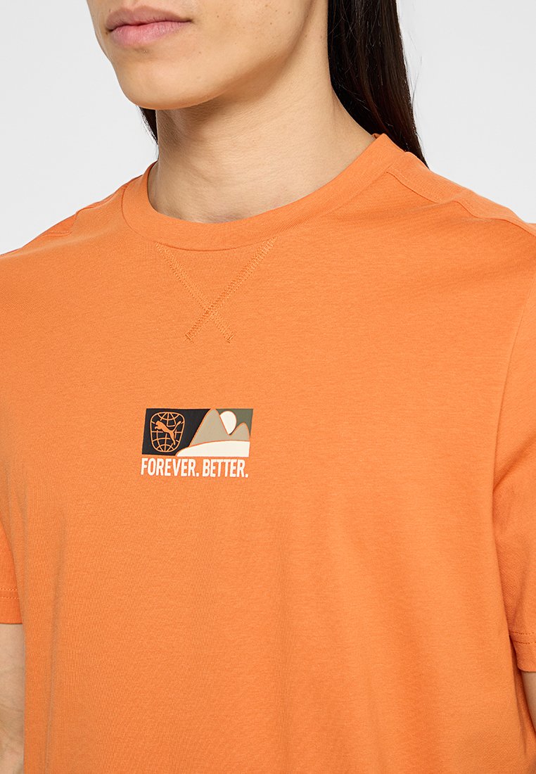 Camiseta de algodón naranja con un gráfico cuadrado que presenta un diseño de un globo terráqueo y montañas, y el texto "FOREVER. BETTER." en un color contrastante.