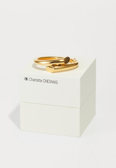Goldene Creolen mit einem glatten, abgerundeten Design, präsentiert auf einer weißen Box mit dem Markennamen "Charlotte CHESNAIS."