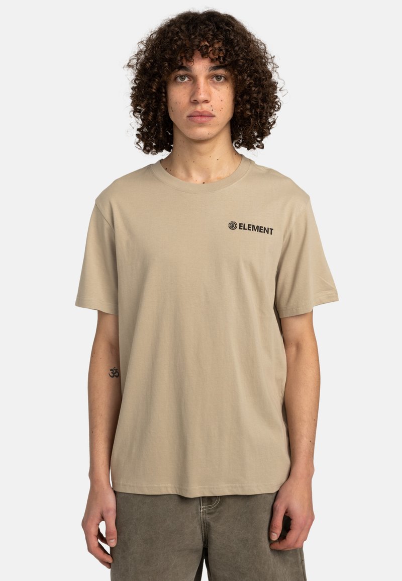 Camiseta de algodón beige con mangas cortas, que presenta un logo negro de "ELEMENT" en el pecho. Diseño sencillo, ajuste relajado, cuello redondo clásico.