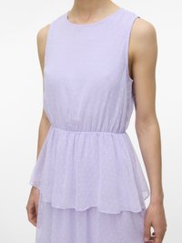 Vasaras kleita bez piedurknēm lavandas krāsā ar teksturētām pūkainām puntēm, elastīgu vidukli un slāņotu pepluma detaļu, ko valkā persona ar tetovējumu augšdelmā.