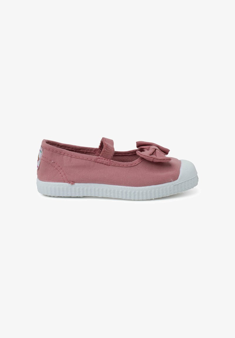 Zapatilla de lona rosa tipo slip-on con un detalle de lazo, puntera de goma blanca y suela blanca texturizada. Presenta un pequeño logo en el lateral.