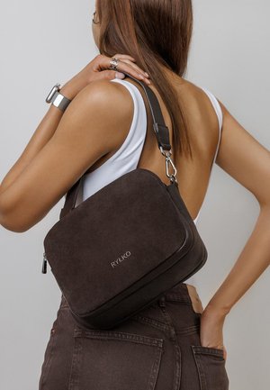 Brūnas zamšādas un teksturētas ādas crossbody soma ar rāvējslēdzēja aizdari, regulējamu siksnu un sudraba detaļām, ar izsmalcinātu zīmola apzīmējumu.