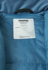 Niebieska kurtka puchowa z miękkim polarem wewnątrz, naszywka z logo "Reima" oraz rozmiar 104/4T, z czarną pętlą do zawieszenia.