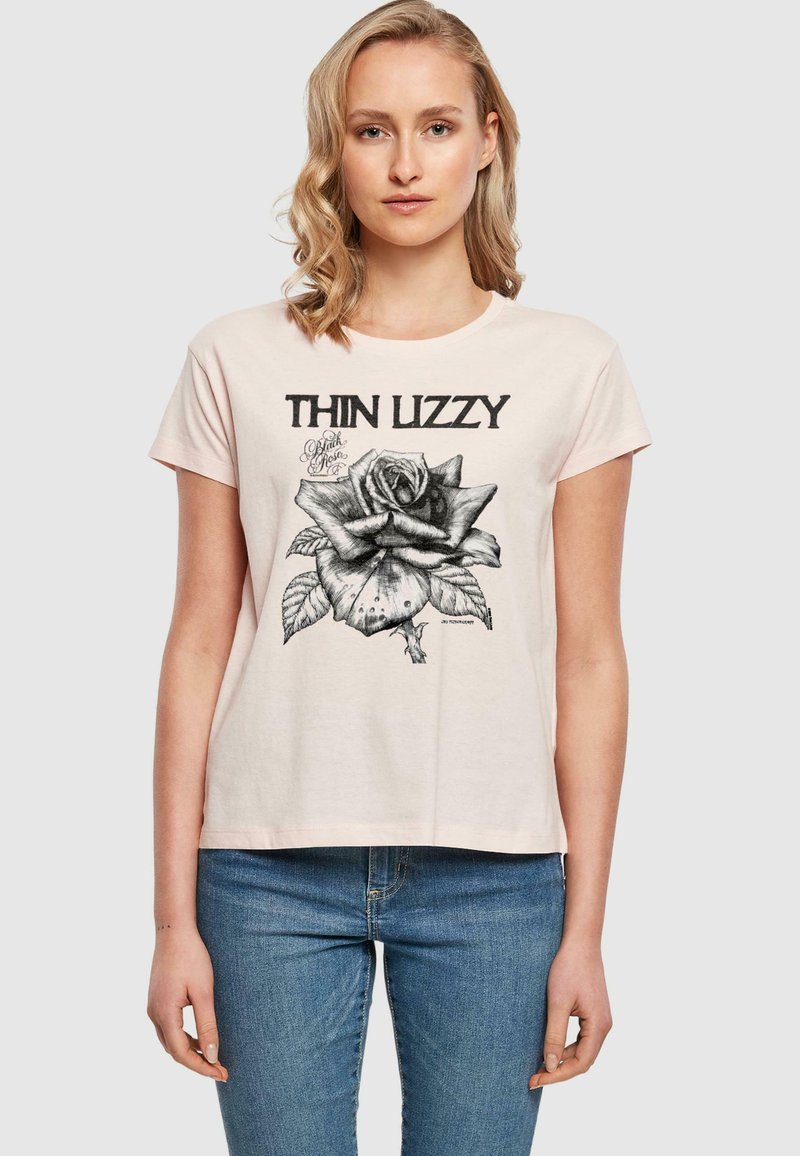 Šviesiai rožinė medvilninė marškinėliai su trumpomis rankovėmis, su juodu grafiniu dizainu, vaizduojančiu rožę, ir tekstu "THIN LIZZY." Su apvalia iškirpte.