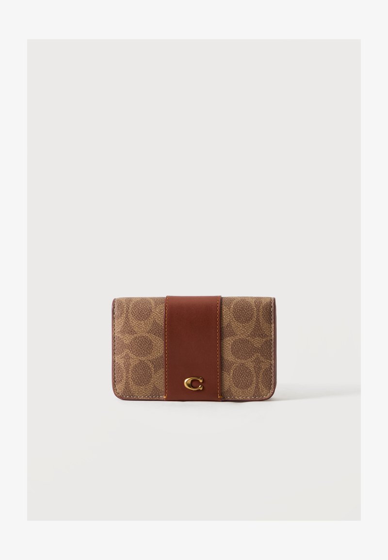 Portefeuille en tissu marron avec motif circulaire, sangle en cuir au centre et petit emblème en métal doré en forme de 'C' à l'avant.