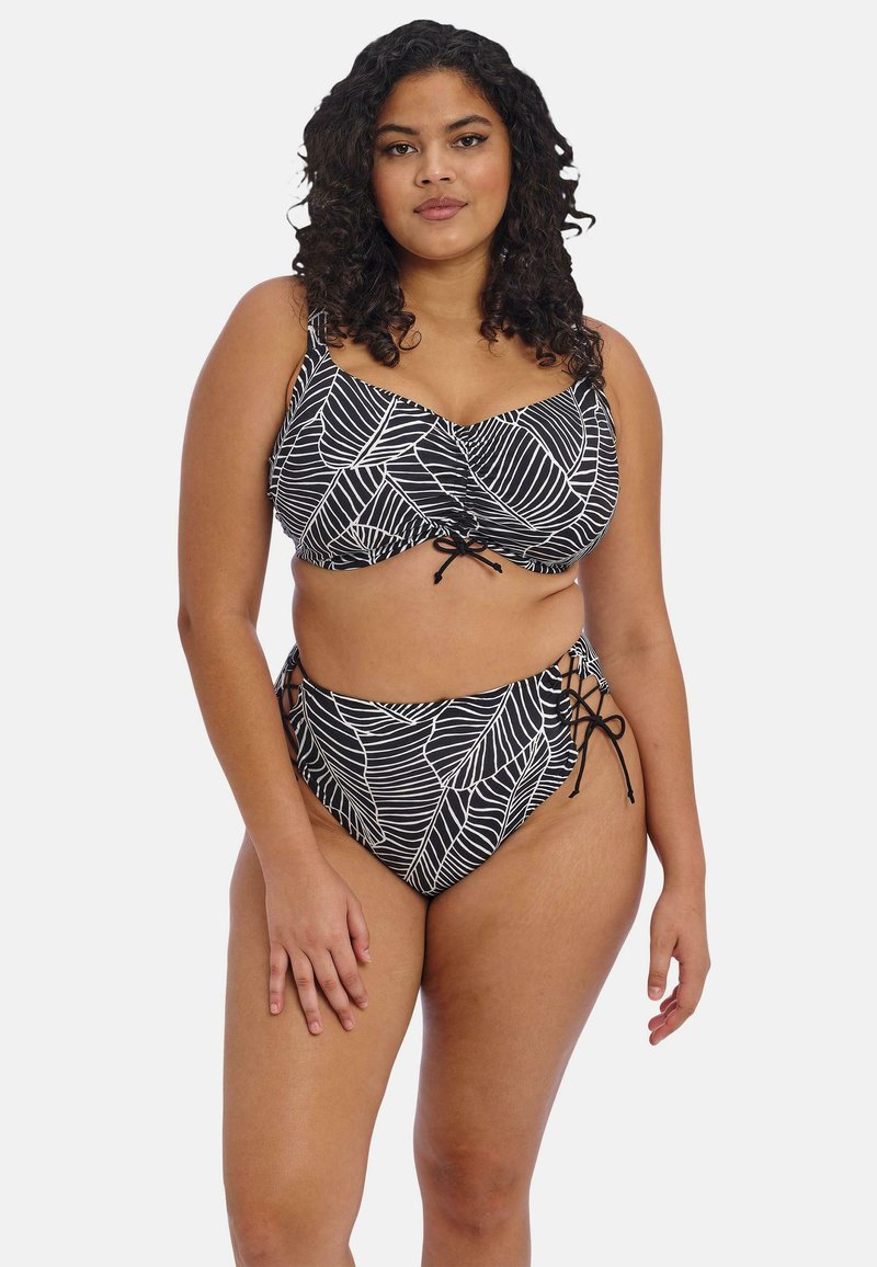 Zwart-wit bikini met een bladdessin, voorzien van een gerimpelde top en een hooggenaaide onderkant. Touwtjes aan de zijkanten van de onderkant.