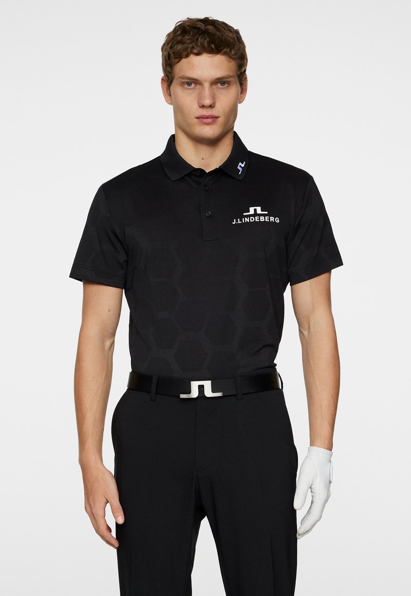 Black polo shirt with hexagonal pattern, short sleeves, and collar. Features logo in white on chest and collar, paired with black pants and white glove.