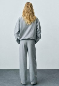 Lichtgrijs op maat gemaakt outfit met een losse sweatshirt met verlaagde schouders en brede broekspijpen met rafelige zomen.