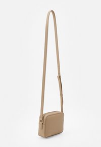 Beige přes rameno taška s texturovaným povrchem, obdélníkový tvar, nastavitelný popruh a zipové uzavření. Jednoduchý design s minimálními detaily hardwaru.