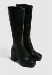 Stivali neri al ginocchio realizzati in pelle liscia, caratterizzati da un tacco a blocco, un gambale ampio e dettagli di cucitura minimi per un design elegante.