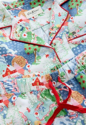 Bavlněný pyžamový set s vícerozměrným vánočním vzorem zobrazujícím domky, stromy a fantazijní postavy. Červené lemování a detaily v pase.