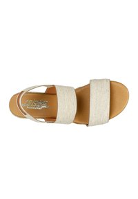 Beige fabric sandals with two wide straps and a brown sole, featuring a textured finish and a metallic logo on the insole.