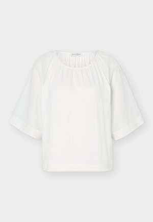 Hvid løs bluse med rund halsudskæring, samlet stof ved kraven og brede halvlange ærmer med vandret stingdetalje.