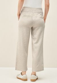 Beige striped wide-leg pants with a textured pattern, featuring a high waistband and two back pockets. Pairing with white sneakers.