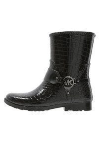 Botte noire brillante à la cheville avec une texture crocodile, bout rond et une sangle avec un accent logo circulaire, dotée d'une semelle en caoutchouc plate.