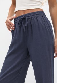 Navyblauwe wijdlopende broek van zachte, gestructureerde stof; heeft een elastische tailleband met een trekkoord voor een verstelbare pasvorm.