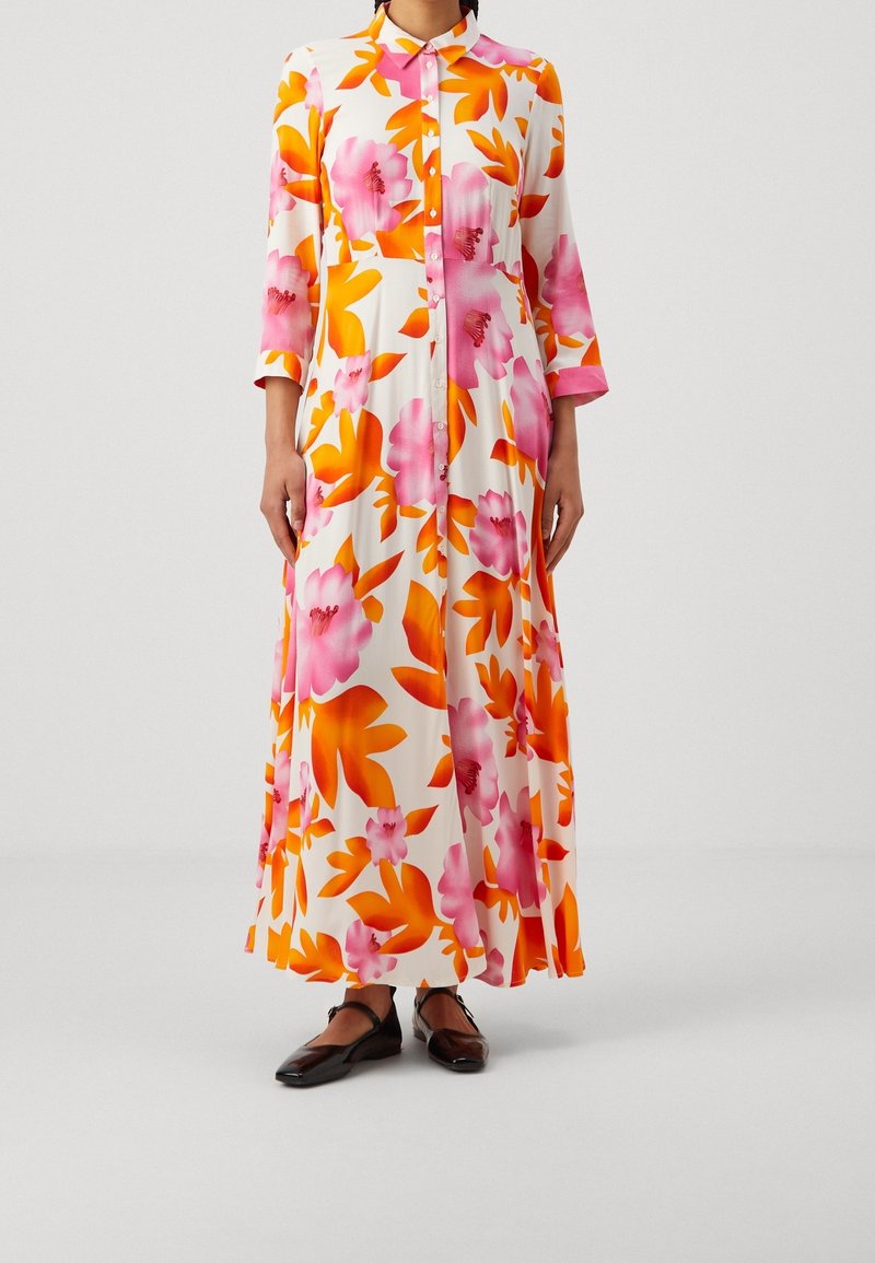 Lungo vestito floreale bianco con motivi rosa e arancione. Chiusura frontale con bottoni, colletto e maniche a tre quarti. Tessuto morbido, lunghezza completa.