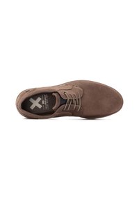 Zapato de ante marrón con puntera redonda, diseño con cordones y plantilla oscura en contraste. Presenta costuras sutiles y detalles en ojetes. Suela plana.