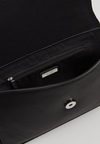 Black leather purse open to show interior with a zippered pocket and a metal brand label reading ALDO.