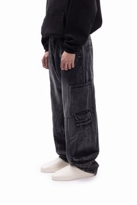 Μαύρο φαρδύ τζιν cargo παντελόνι με πολλαπλές τσέπες, ξεθωριασμένη υφή και άνετη εφαρμογή. Συνδυασμένο με μινιμαλιστικά λευκά υποδήματα.