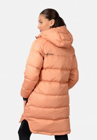 Manteau en duvet pêche avec capuche, présentant un design matelassé, une fermeture éclair, et des accents noirs sur les poignets. La longueur atteint mi-cuisse.