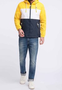 Chaqueta a bloques de color en amarillo, blanco y azul marino; cuenta con capucha, cierre de cremallera y dos bolsillos laterales con acentos de hardware.